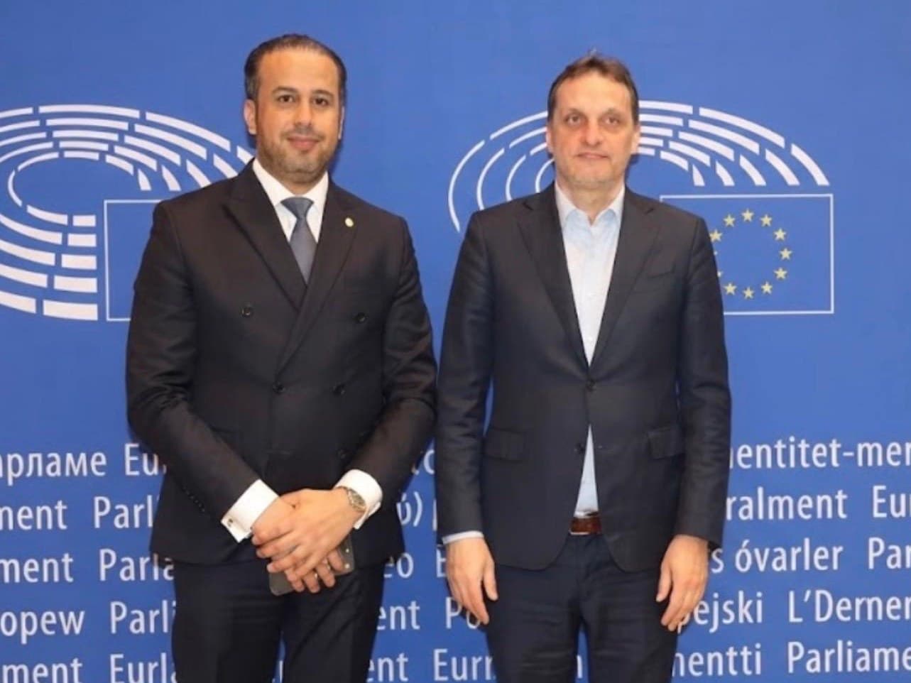 Kamal Benali with a delegate in front of the European Parliament backdrop